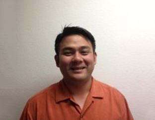 A man in an orange shirt smiling for the camera.
