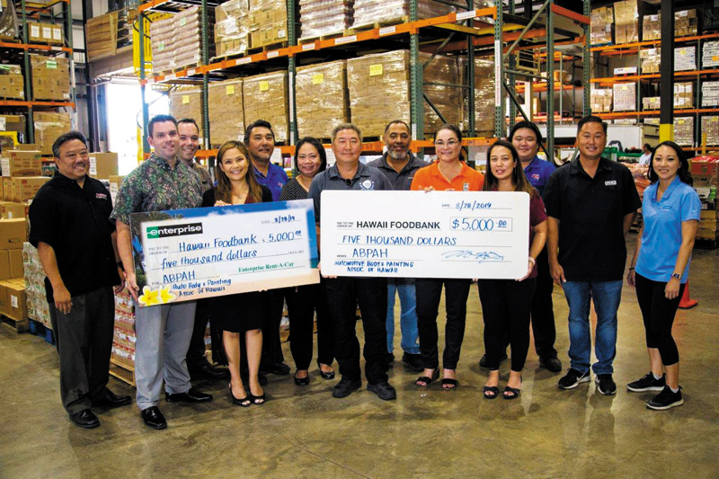 A group of people holding large checks in front of boxes.